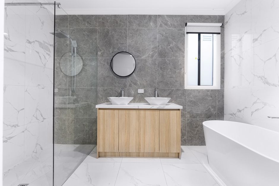 Completed bathroom installation in a Liverpool terraced house showing walk-in shower, full wall tiling and vanity unit